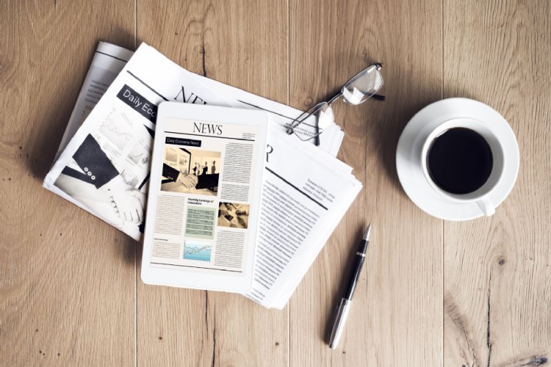 Zeitung mit Tasse Kaffee ist auf einem Schreibtisch